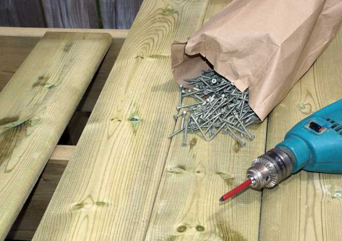 Screws and a drill are shown on top of wood planks