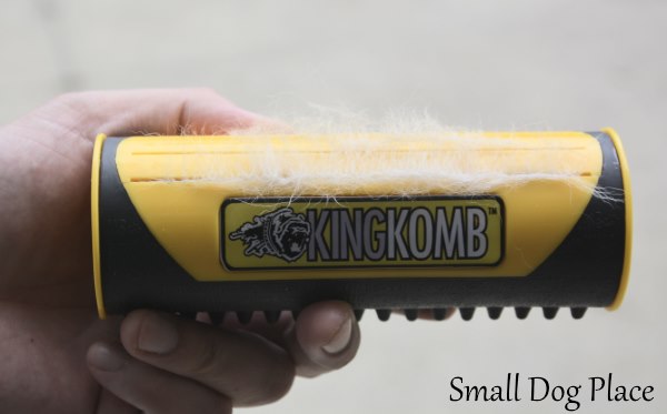 The stainless steel combs are now retracted on the King Komb dog deshedding tool, showing the hair that has accumulated on the side.