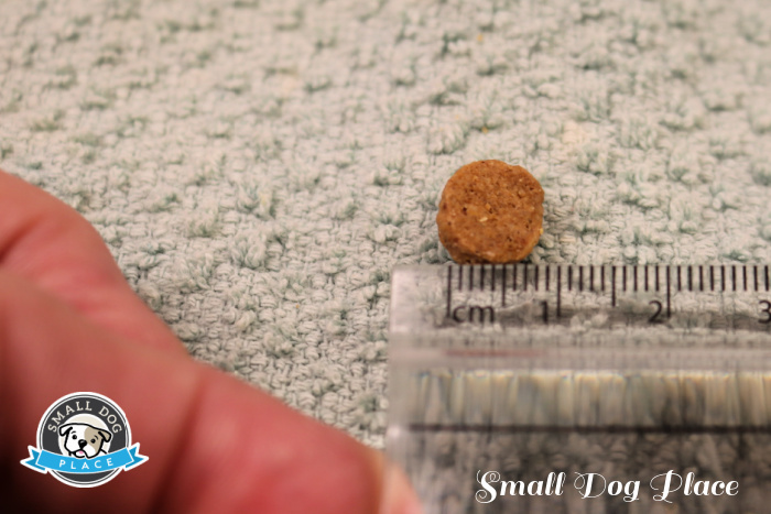 Shown is a piece of kibble being measured with a metric scale ruler