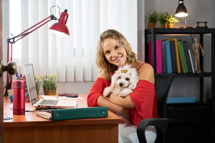 A young woman is holding a small white dog.