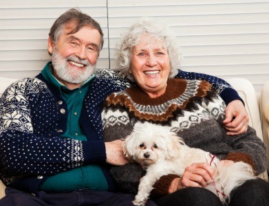 An older couple holding a small dog