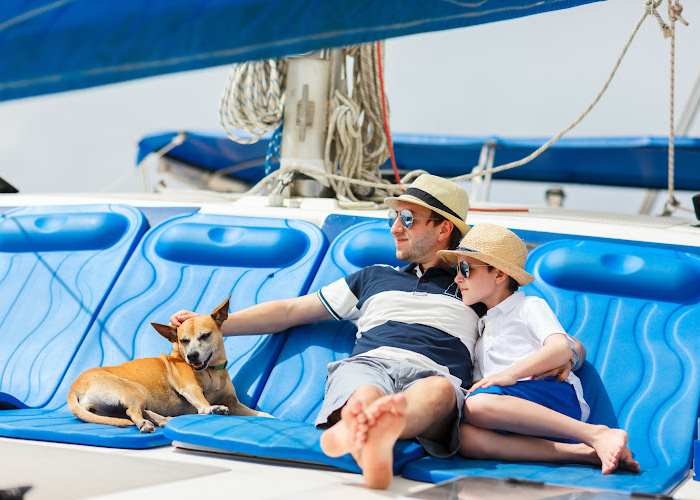 Two people and a small dog are sailing on a boat