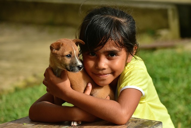 A young girl is holding her young puppy