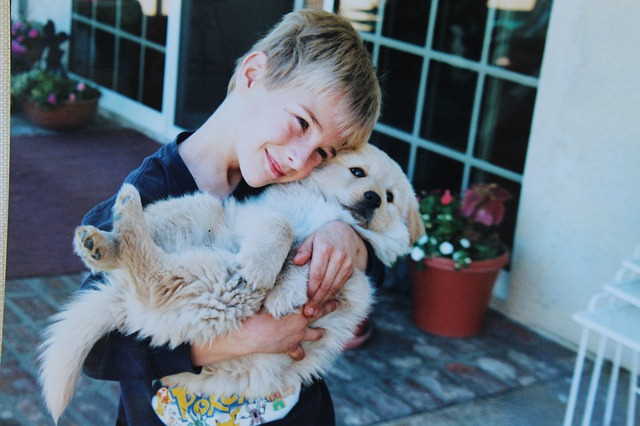 A boy is snuggling with his puppy.