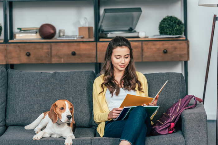 A college student is studying with her beagle by her side