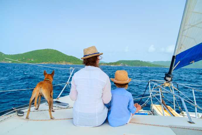 Mother and son along with a dog are sitting on board a sailing ship.