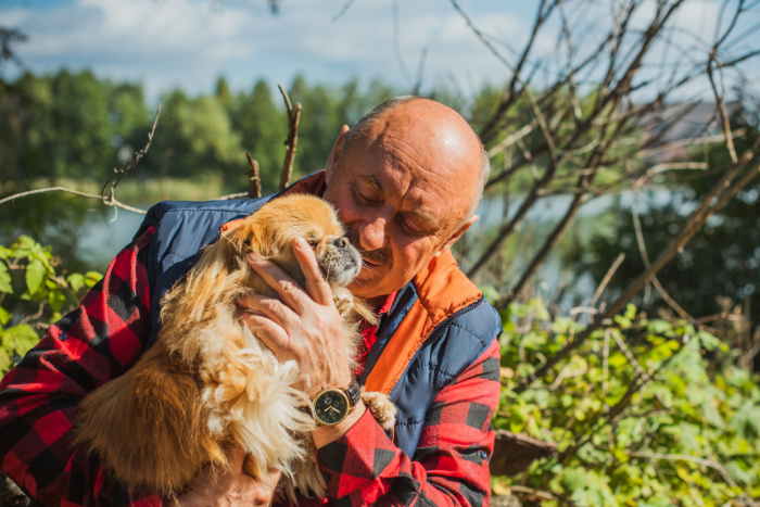 A man holding a small dog outdoors