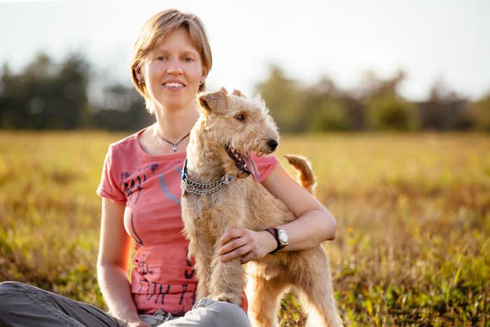 A young woman is holding a lakeland terrier