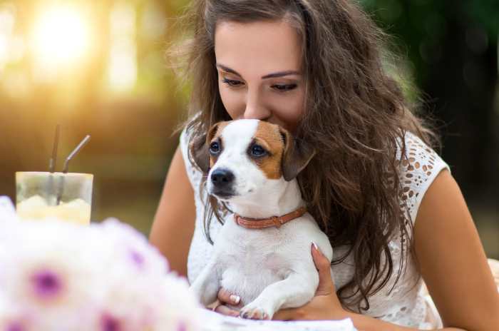 A woman is cuddling her small dog