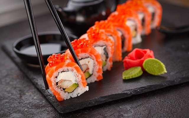 Sushi roll showed with chopsticks.